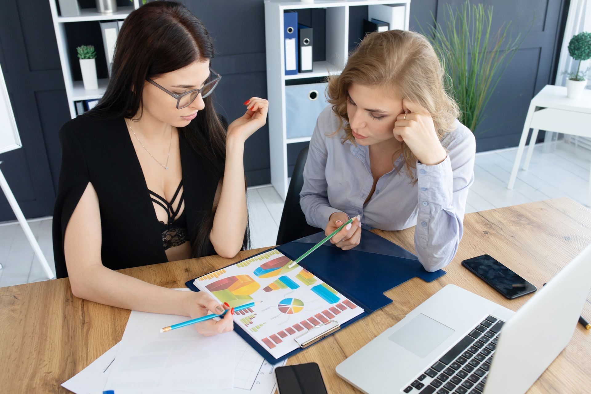 Two business woman investment consultant analyzing company annual financial report balance sheet statement working with documents graphs. Concept picture of economy, market, office, money and tax.